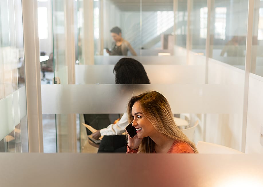 A woman at an office's phone booth taking a call with her smartphone. — Vergani Fotografia // Shutterstock