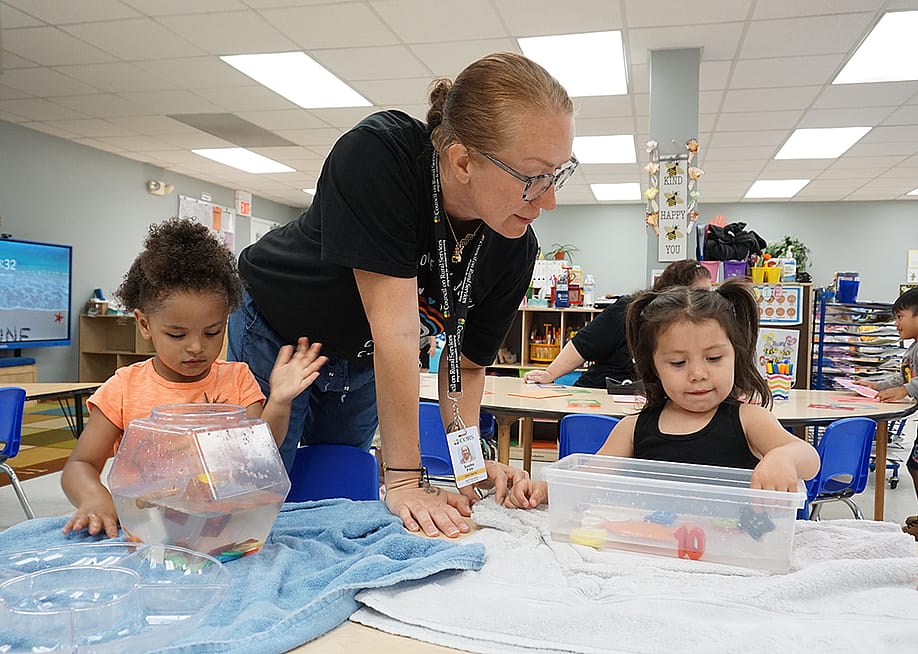 Head Start teacher Sasha Fair helps two preschool children with a science experiment. — Jackie Mader for The Hechinger Report