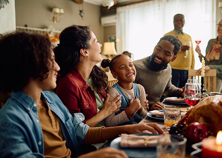 A big family laughing during Thanksgiving dinner at home. — Drazen Zigic // Shutterstock