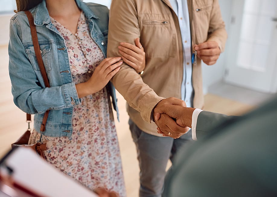 A couple shaking hands with a real estate agent after purchase. — Drazen Zigic // Shutterstock