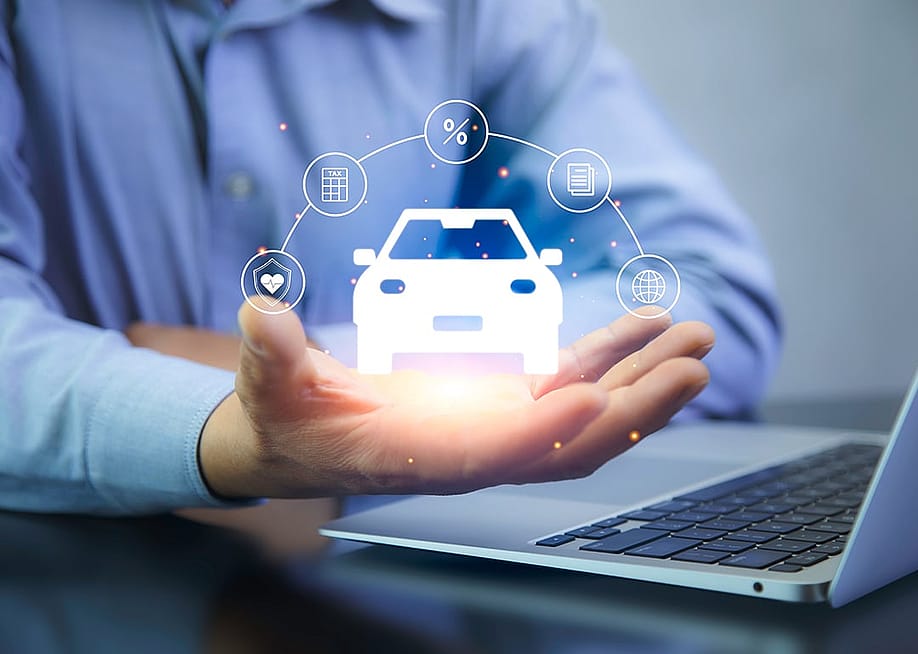 A car insurance agent using a laptop with graphics of car insurance concepts illustrated over his hand. — tech_BG // Shutterstock