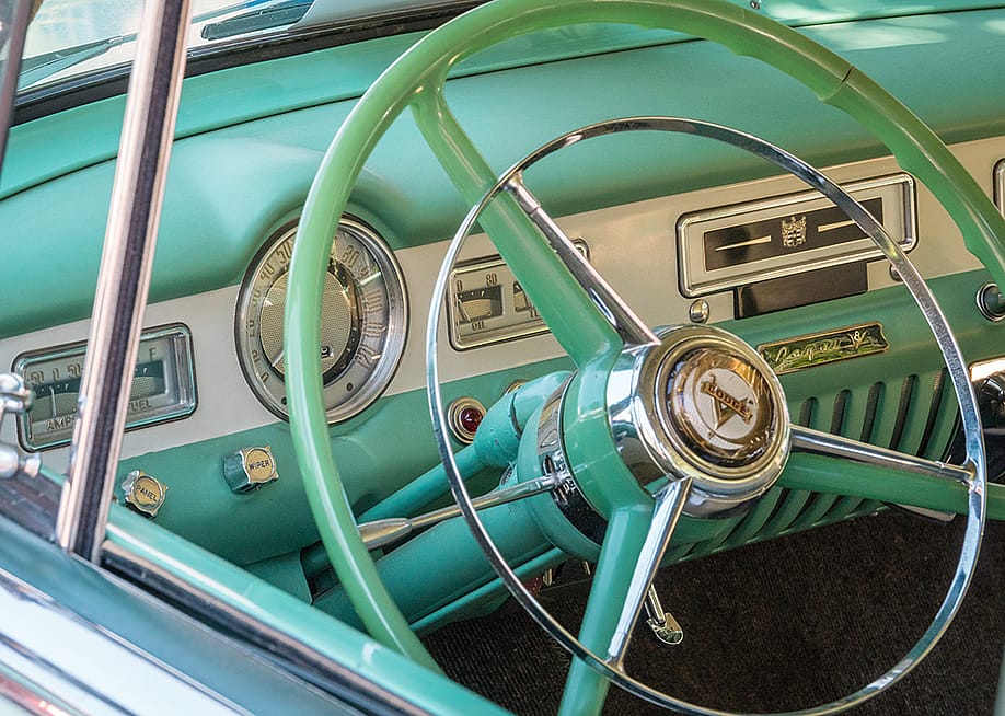 A close up view on a vintage pastel green car's steering wheel. — Heidi Besen // Shutterstock