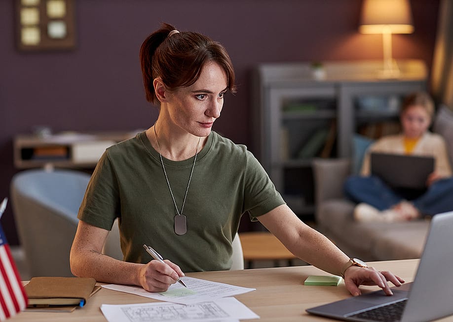 A young military woman browsing information using a laptop in an office. — SeventyFour // Shutterstock
