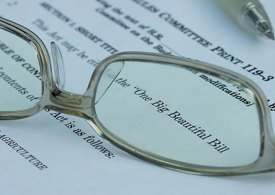 A pair of eyeglasses magnified on the words 'One Big Beautiful Bill' (Act) on a document. — Tada Images // Shutterstock