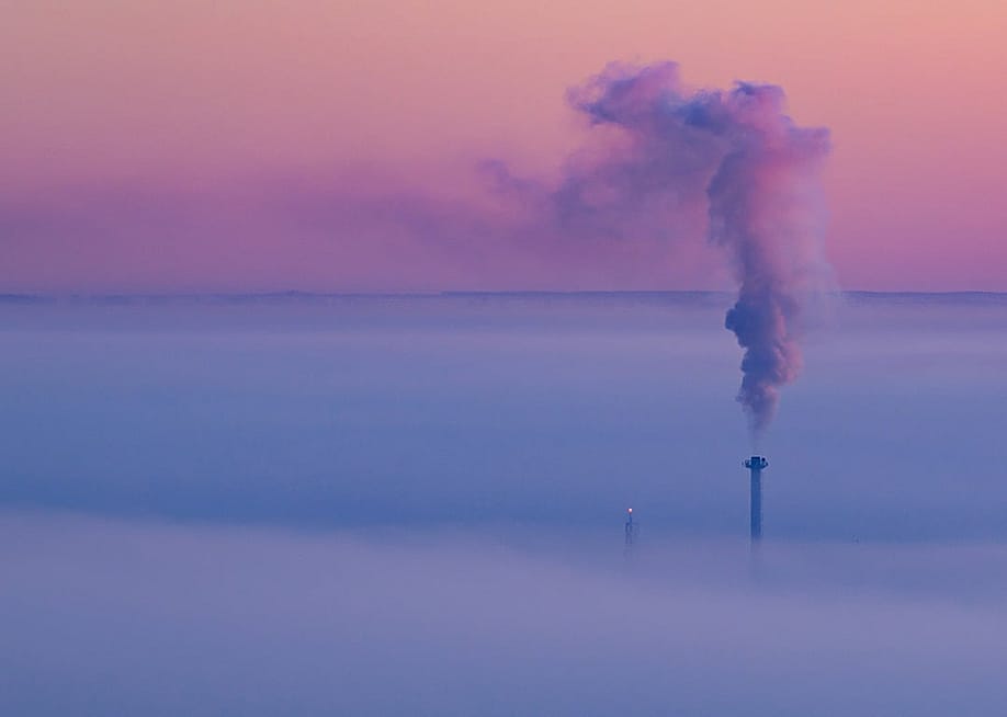 Smoke coming out of a heat and power plant chimney, blending with a lavender morning sky. — Patrick Pleul // picture alliance via Getty Images
