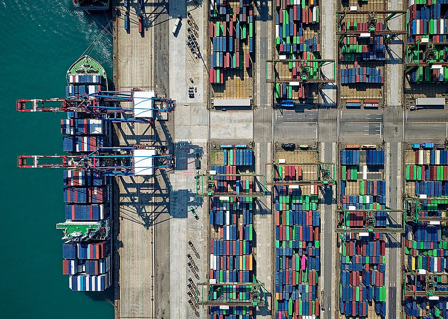 Aerial view on ships, cranes, and cargo containers by the quayside of a dock. — AaronChenPS2 // Shutterstock