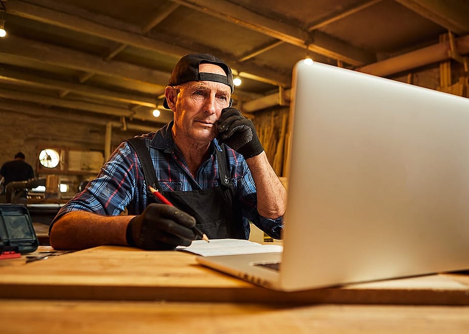 A senior male carpenter working with a client online from their workshop. — BONDART PHOTOGRAPHY // Shutterstock
