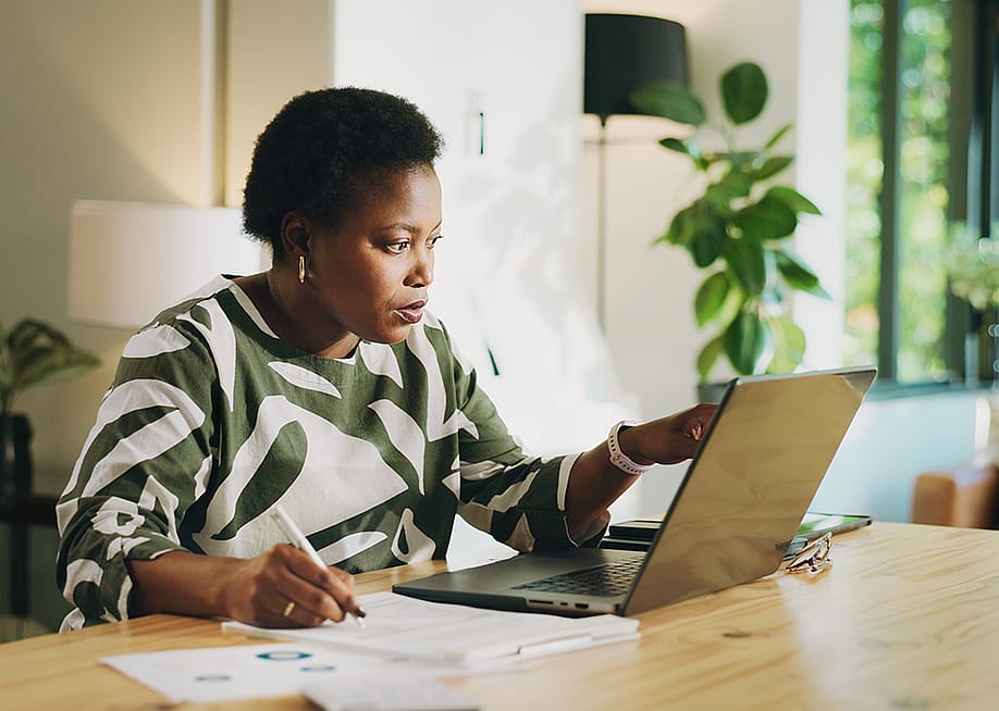 A black female bookkeeper working with a laptop and financial reports at home. — PeopleImages // Shutterstock