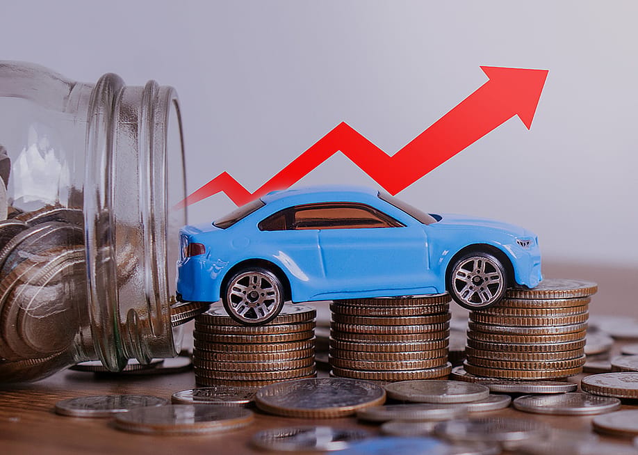 Increase price of car depicted by a small figure of a car over a stack of coins with a red upwards arrow. — witsarut sakorn // Shutterstock