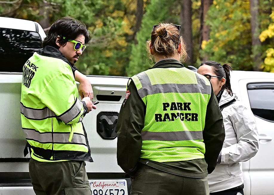 Three park rangers behind their car on duty at Curry Village in the Yosemite Valley at Yosemite National Park, California. — FREDERIC J. BROWN // AFP via Getty Images