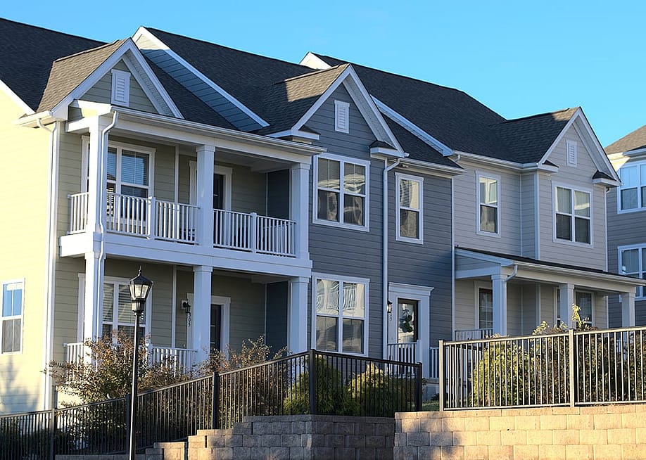 A row of townhouses with grey and white exterior in a housing community. — Karl Cox // Shutterstock