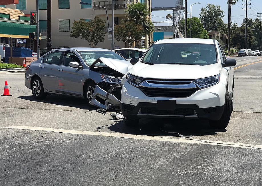Two modern vehicles involved in a traffic accident are shown stopped in an intersection during the day in Los Angeles. — Kilmer Media // Shutterstock