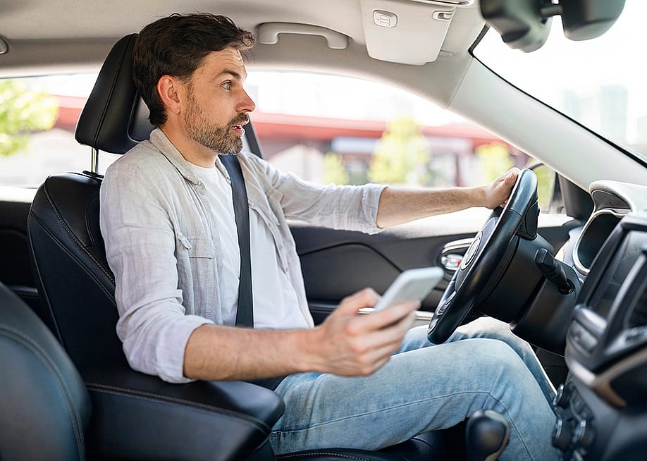 A male driver in shock as he is texting while driving. — Prostock-studio // Shutterstock
