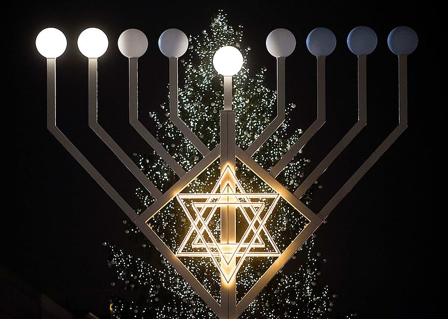 Bulbs symbolizing candles have lit on the 30 foot-tall Hannukah menorah by the Jewish education centre 'Chabad Lubawitsch' in front of a Christmas tree at the Brandenburg Gate in Berlin, Germany. — Gregor Fischer // picture alliance via Getty Images