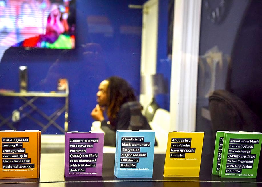 Jon'Aric Nathaniel waits from his clinical appointment at Open Arms Healthcare Center behind a window lined by pamphlets in the foreground on HIV. — Jahi Chikwendiu // The Washington Post via Getty Images