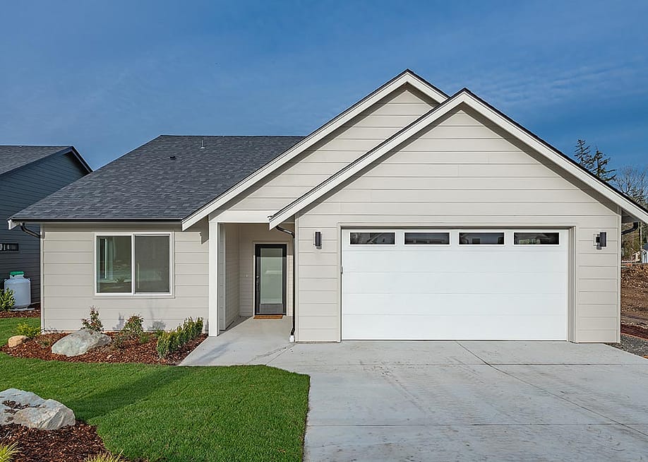 Middle class home exterior small rambler style house with simple style brand new construction blue sky green grass winter season family residence in a suburban neighborhood. — Sheila Say // Shutterstock