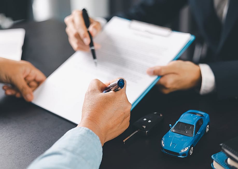 A customer signs a car purchase contract. — jd8 // Shutterstock