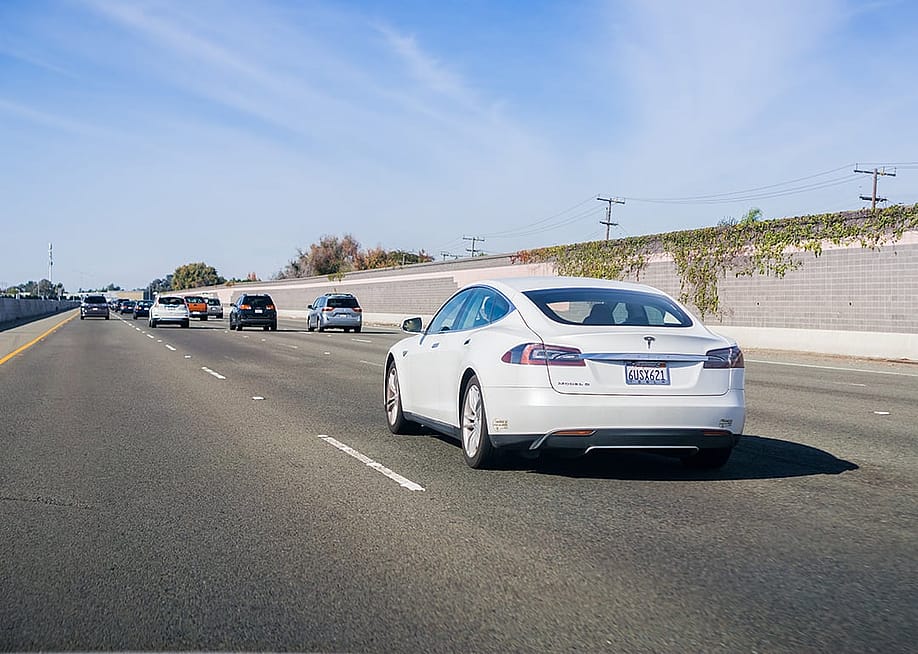 A white Tesla Model S driving on a freeway in San Francisco, California. — Sundry Photography // Shutterstock