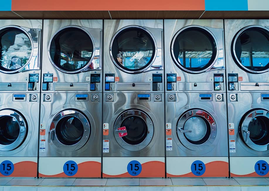 Rows of large industrial laundry machines in a laundromat. — Roman Zaiets // Shutterstock