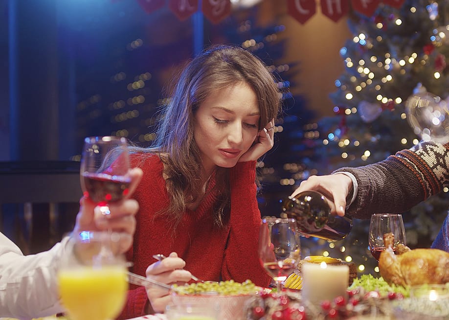 A young woman losing interest or appetite at a Christmas dinner table. — Fractal Pictures // Shutterstock