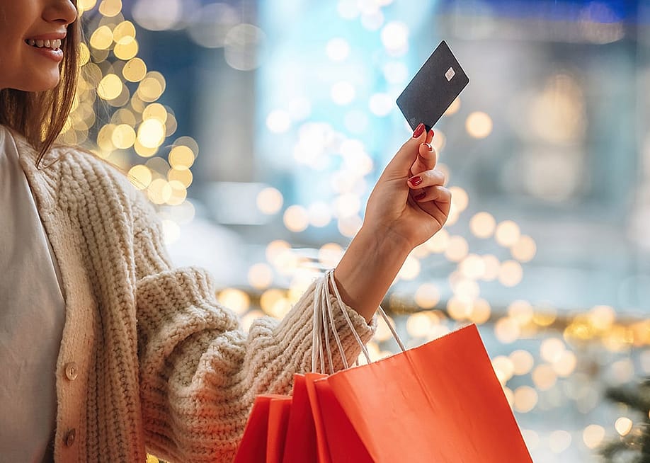 A woman with shopping bags on her arm and holding up a credit card. — Standret // Shutterstock