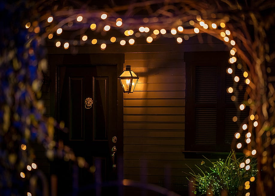 Holiday lights during night designed around an arch leading to a house's doorway. — arthurgphotography // Shutterstock