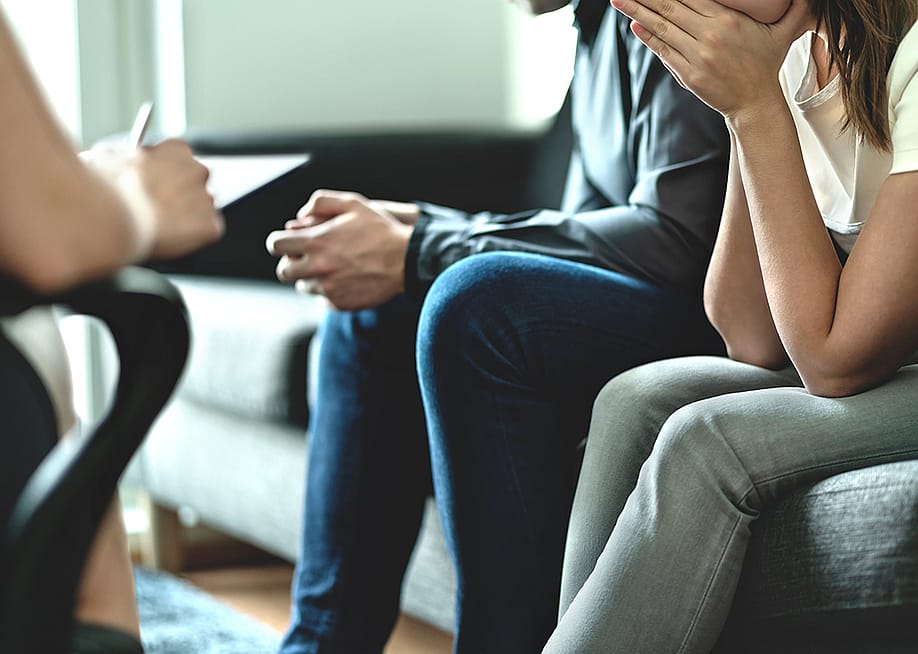 A couple sitting on a sofa during a marriage counseling session. — Tero Vesalainen // Shutterstock