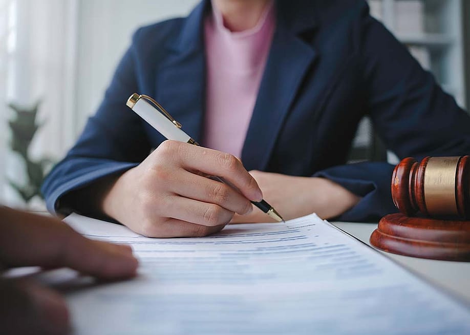 Torso of a female lawyer signing a document for a client in their office. — Amnaj Khetsamtip // Shutterstock