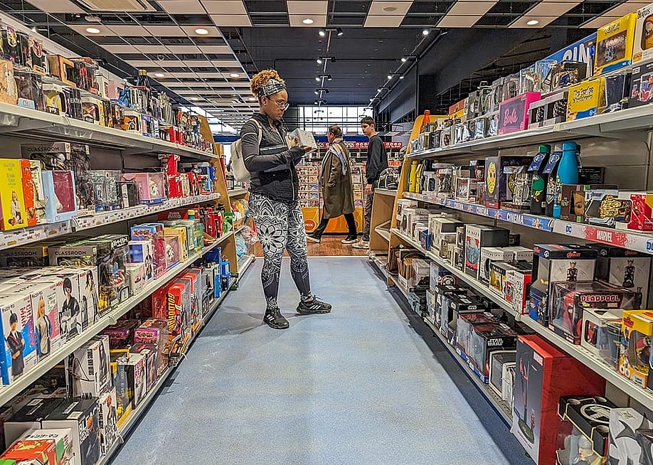 A young adult browsing in a toy and hobby shop aisle. — Henry Saint John // Shutterstock
