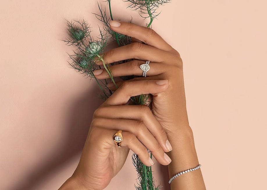 Hands of a bride holding flowers and showcasing diamond cut rings. — VRAI