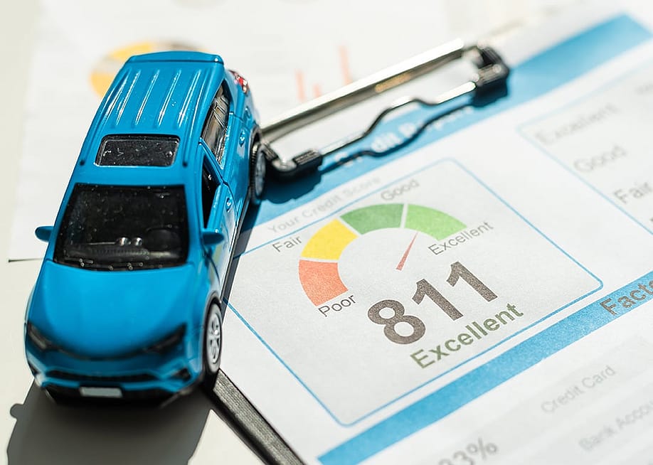 A mini figure of a blue car on top of a credit score report document. — Andrew Angelov // Shutterstock