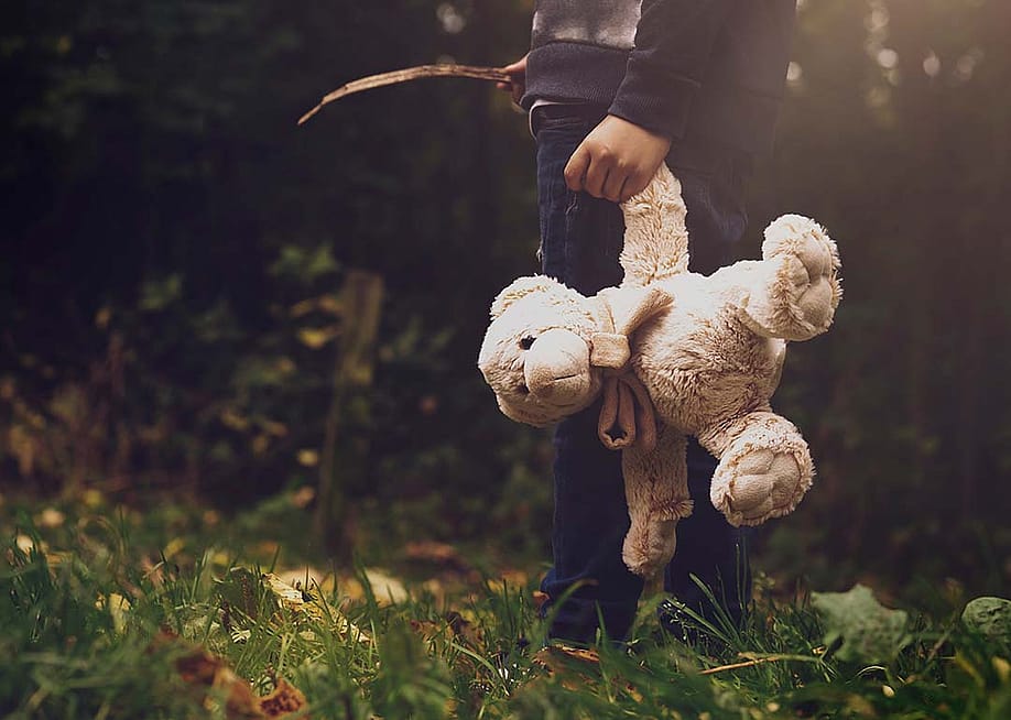 A young boy holding a teddy bear outdoors. — Ann in the uk // Shutterstock