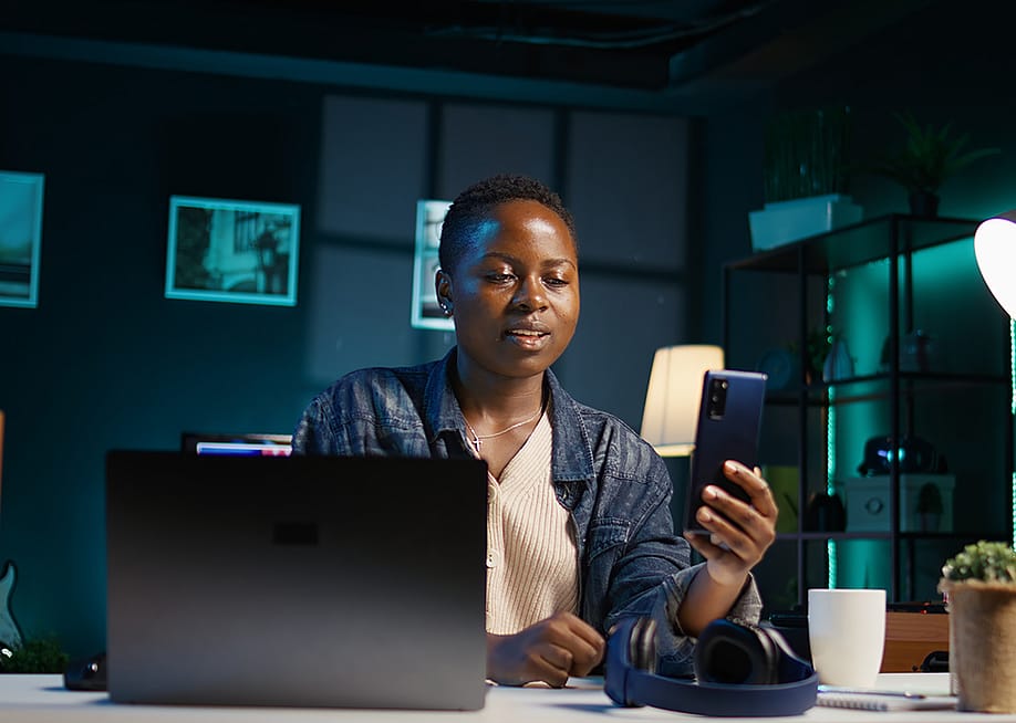 A black female professional answering a video call on her phone while working from home. — DC Studio // Shutterstock