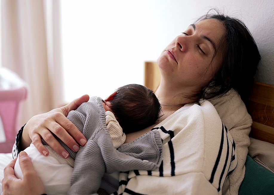 A tired mother sleeping with her newborn on her chest. — Bricolage // Shutterstock