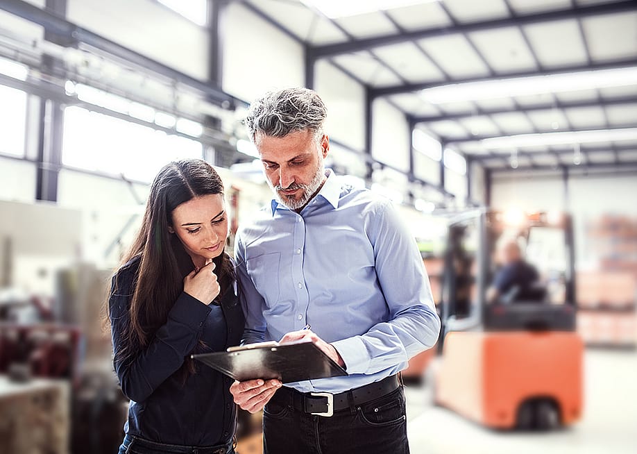 Warehouse manager and employee planning transport process in warehouse. — Halfpoint // Shutterstock