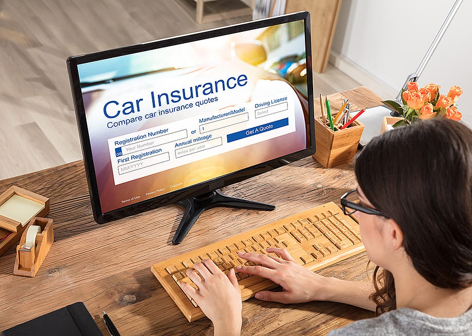 A businesswoman filling out a car insurance form using a desktop. — Andrey_Popov // Shutterstock