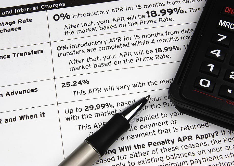 A pen and calculator on top of a credit terms report. — Kreative Photography // Shutterstock