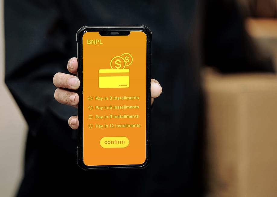 A person holding a smartphone displaying installment options for Buy Now, Pay Later method. — Jutharat Jaroenwong // Shutterstock