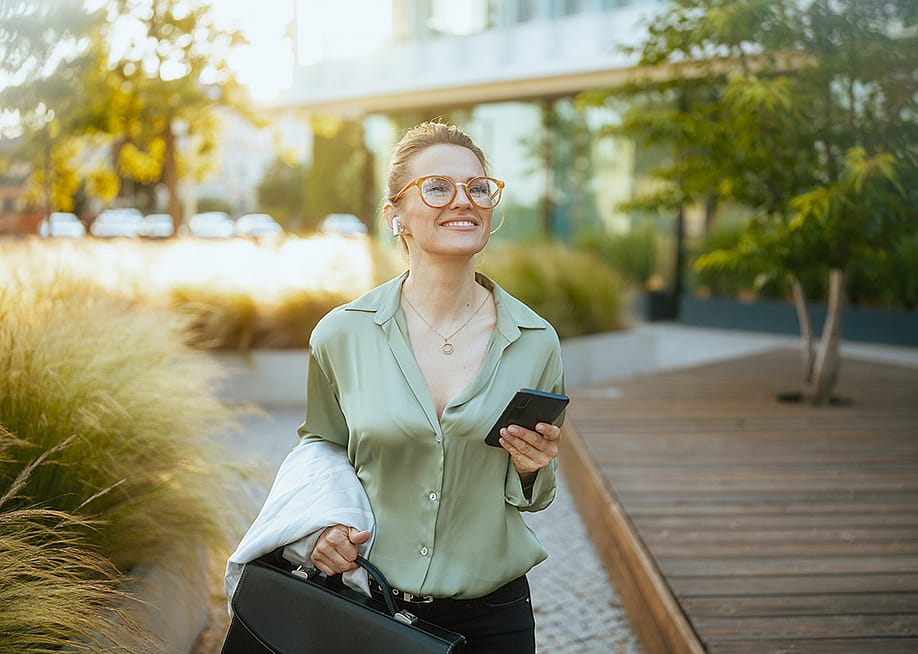 A businesswoman heading to work with a briefcase and listening to wireless earphones. — Alliance Images // Shutterstock