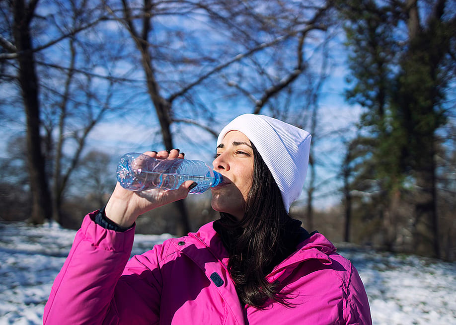 A female athlete in winter clothes drinking water outdoors. — Aleksandar Malivuk // Shutterstock