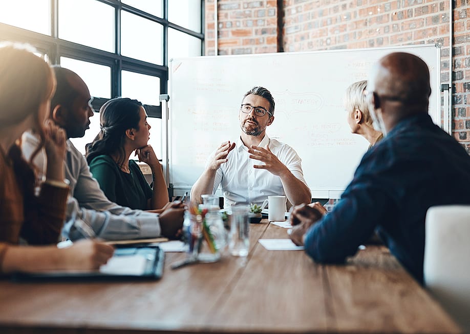A manager leading a team meeting in a boardroom. — PeopleImages // Shutterstock