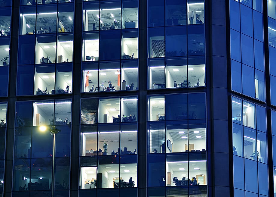 Glass facade of a modern corporate building during night. — Grand Warszawski // Shutterstock