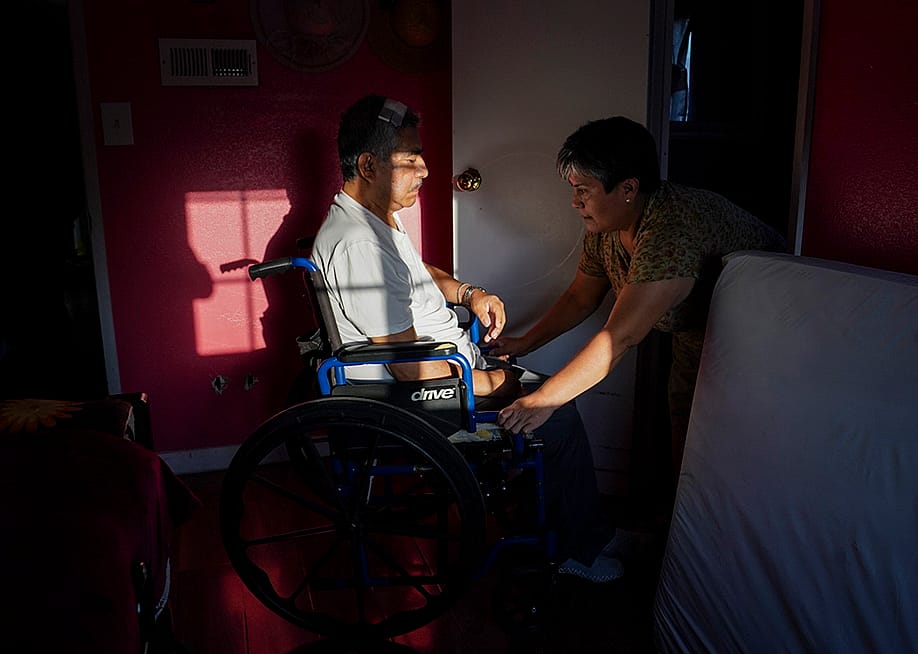 Maria Patricia Alcantara (R), wheels Jose Epifanio Sanchez Trujeque (L) to the bathroom at their home in Lebec, California. — Carolyn Van Houten // The Washington Post via Getty Images