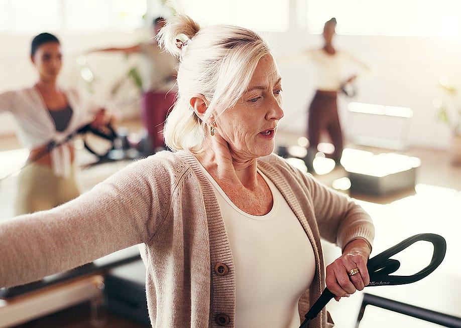 A mature female fitness coach leading a pilates class. — PeopleImages // Shutterstock