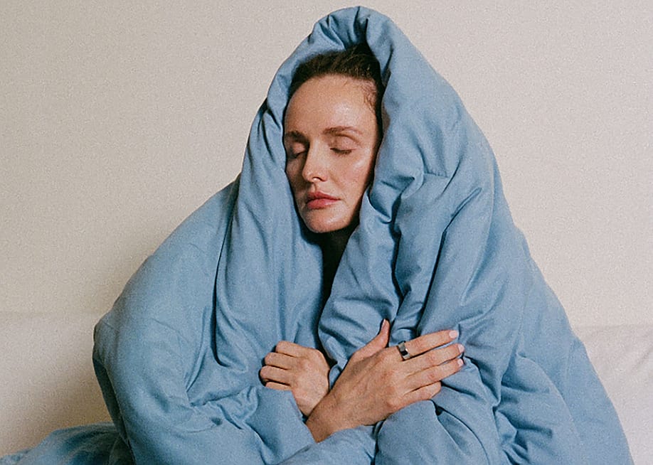 A sleepy woman covering her head with a blue blanket. — Oura