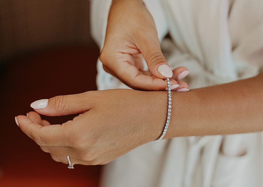 A bride putting on an elegant bracelet on her left wrist. — Leephotos.ae // Shutterstock