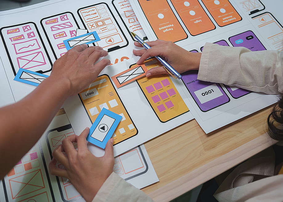 Web designers arranging cutouts to visualize a mobile app interface project. — PreciousJ // Shutterstock