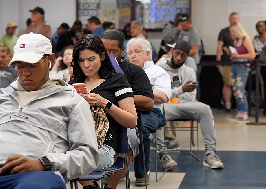 People seated for a queue where most are waiting by being on their phones. — Erin Deleon // Shutterstock