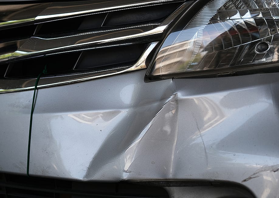A car's bumper dented from a hit. — wisely // Shutterstock