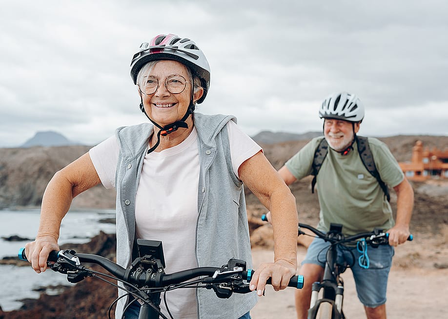 A senior couple riding their bikes on the beach. — Perfect Wave // Shutterstock